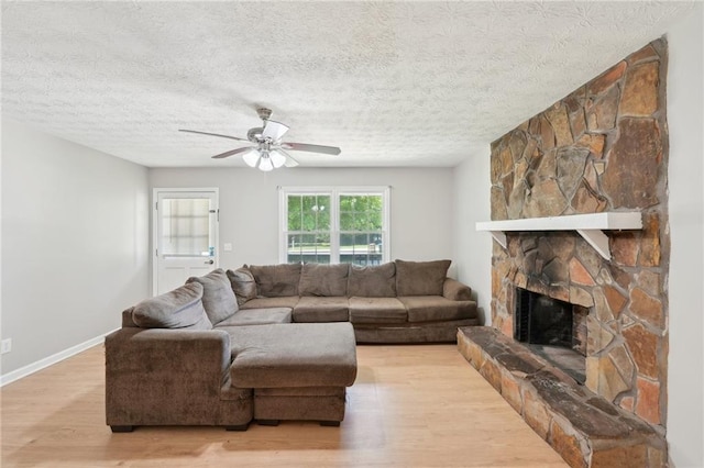 3388 Hamilton Mill Rd, Buford, GA 30519 - living area with light wood-style floors, a ceiling fan, a stone fireplace, a textured ceiling, and baseboards