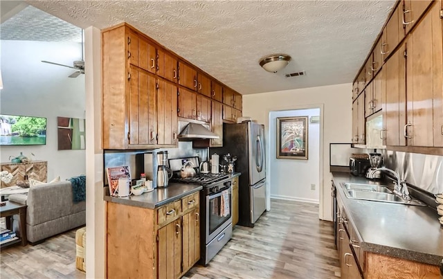 kitchen with ceiling fan, appliances with stainless steel finishes, a textured ceiling, light wood-type flooring, and sink