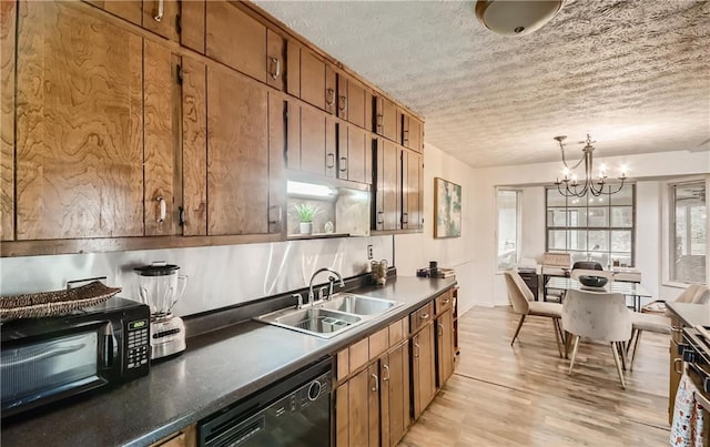 kitchen with black dishwasher, sink, a notable chandelier, a textured ceiling, and light hardwood / wood-style floors