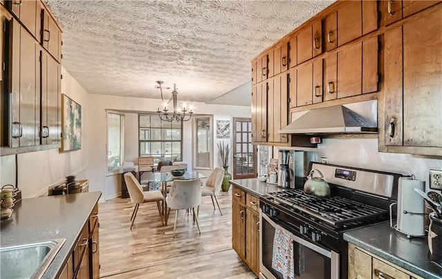 kitchen featuring a textured ceiling, a chandelier, stainless steel gas stove, pendant lighting, and light hardwood / wood-style floors