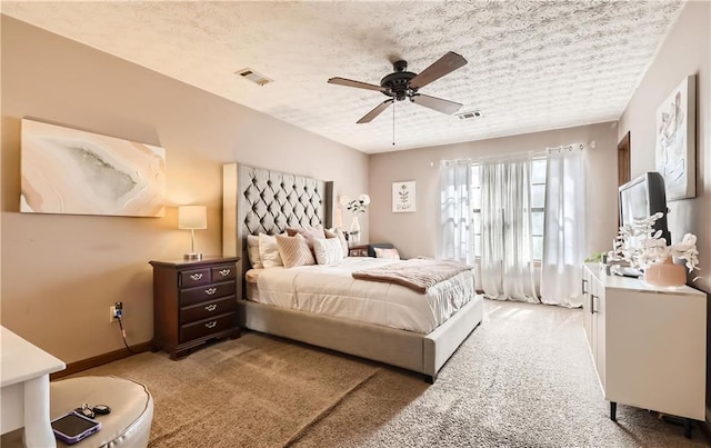 bedroom featuring a textured ceiling, light colored carpet, and ceiling fan