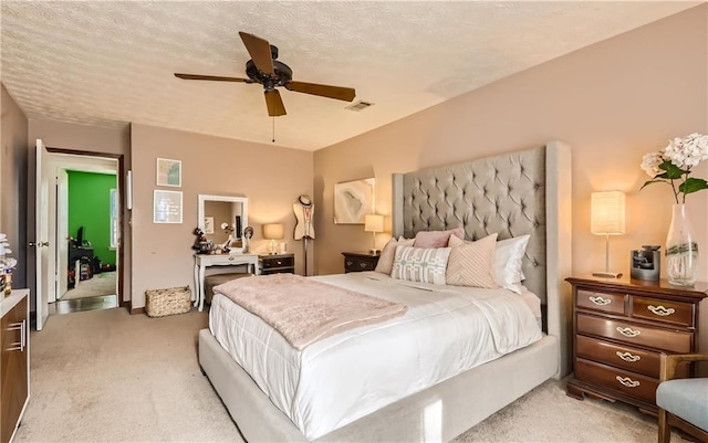 bedroom with a textured ceiling, light colored carpet, and ceiling fan