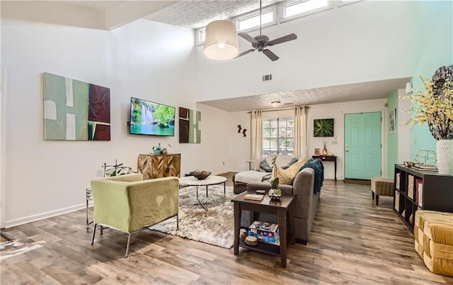 living room featuring ceiling fan, a towering ceiling, and hardwood / wood-style floors