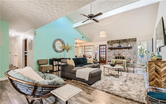 living room featuring a stone fireplace, a textured ceiling, wood-type flooring, and a wealth of natural light