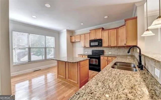 kitchen featuring a sink, decorative backsplash, black appliances, light wood finished floors, and crown molding