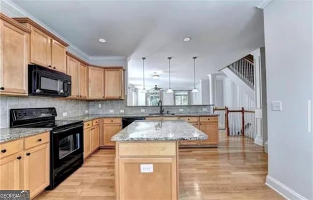 kitchen with a peninsula, black appliances, backsplash, and a sink