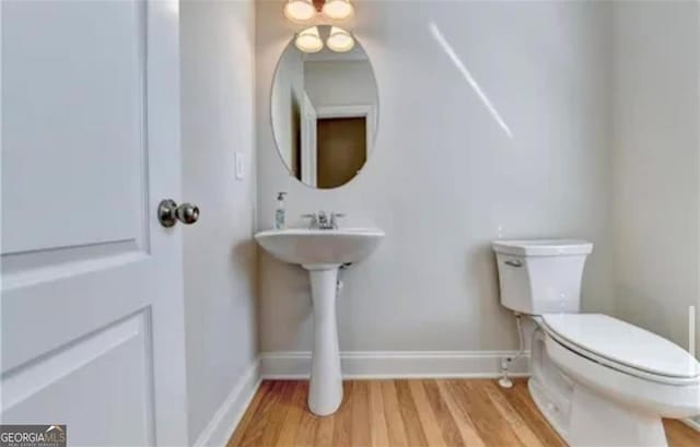 bathroom featuring wood finished floors, toilet, and baseboards