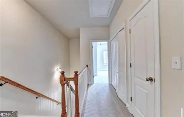 corridor with attic access, light colored carpet, and an upstairs landing