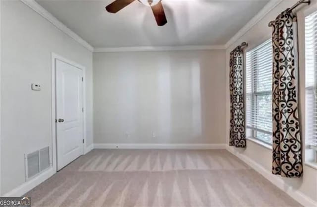 carpeted spare room featuring ornamental molding, a wealth of natural light, and visible vents