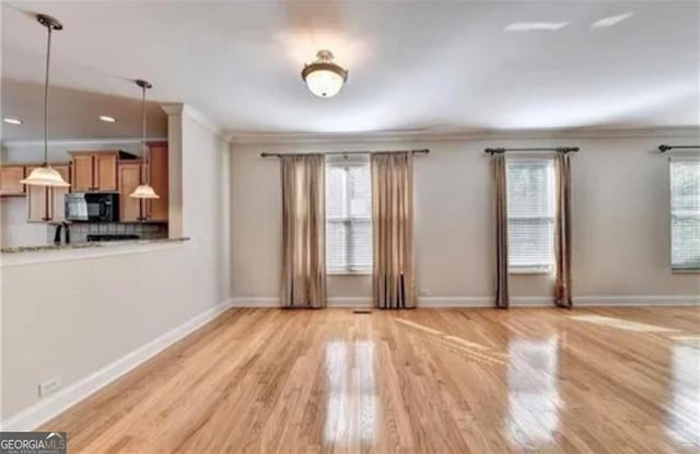 unfurnished living room featuring baseboards, crown molding, and light wood finished floors