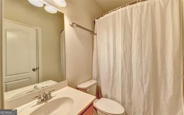 full bath with a shower with curtain, vanity, and toilet