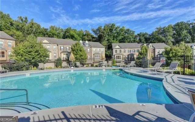 community pool featuring a residential view, fence, and a patio