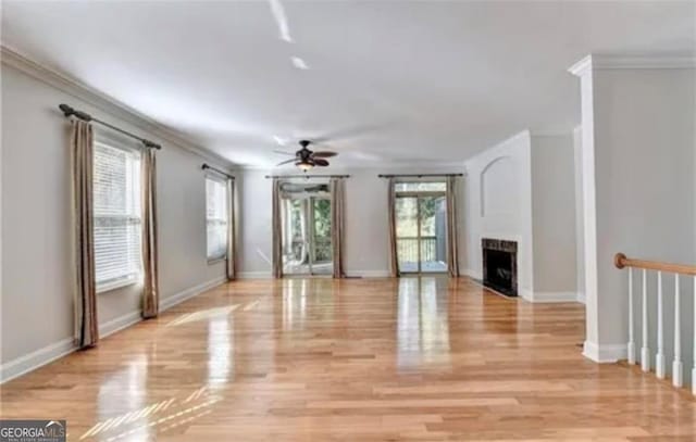 unfurnished living room featuring light wood finished floors, a fireplace, and ornamental molding