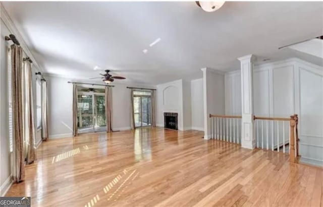 unfurnished living room with ornamental molding, a ceiling fan, light wood-style flooring, and baseboards