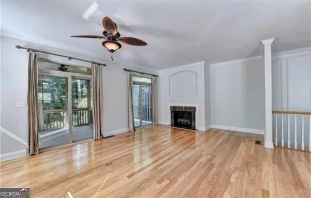 unfurnished living room featuring wood finished floors, a fireplace with flush hearth, a ceiling fan, and crown molding