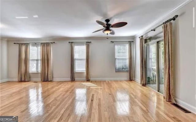 unfurnished room featuring ornamental molding, light wood-style floors, visible vents, and a healthy amount of sunlight