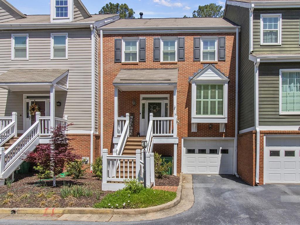 multi unit property featuring a garage, aphalt driveway, and brick siding
