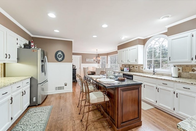 kitchen featuring visible vents, white cabinets, and a sink