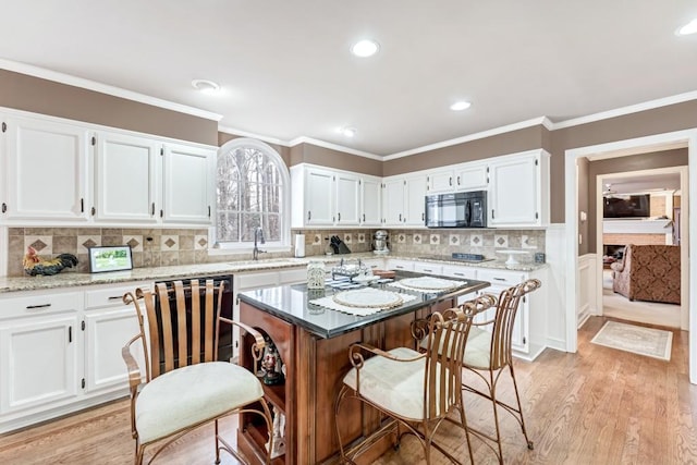 kitchen with white cabinets, black appliances, ornamental molding, and a sink