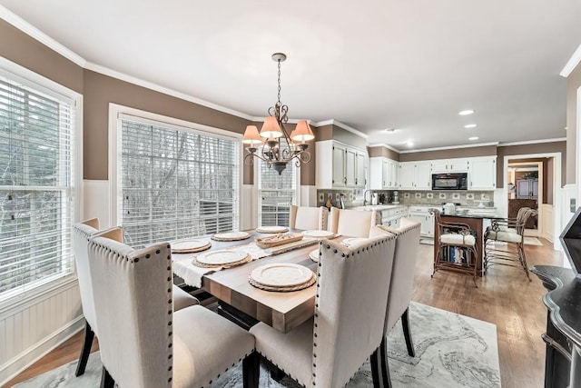 dining area with a wainscoted wall, a wealth of natural light, and a chandelier