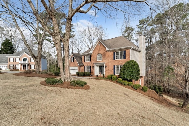 view of front of home with a front lawn, driveway, a chimney, and a garage