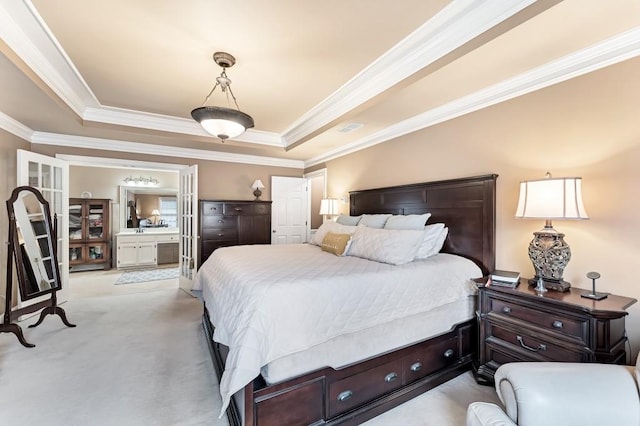 bedroom with visible vents, light carpet, a tray ceiling, ensuite bath, and crown molding