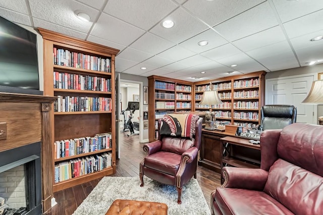 living area with recessed lighting, wall of books, wood finished floors, and a fireplace