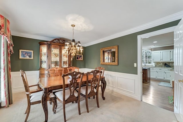 dining room featuring a decorative wall, wainscoting, crown molding, and an inviting chandelier