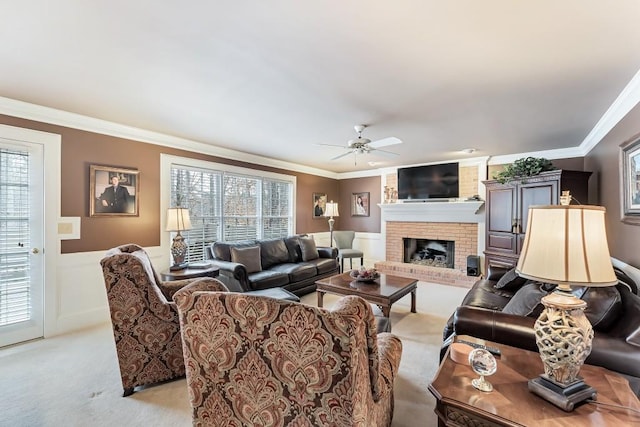 living area with a wainscoted wall, light colored carpet, ceiling fan, and crown molding