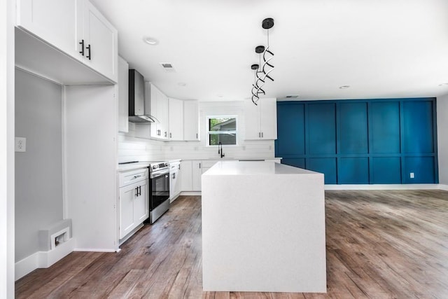 8420 Sheridan Dr, Jonesboro, GA 30236 - kitchen with stainless steel electric range oven, wall chimney range hood, a center island, backsplash, and white cabinetry