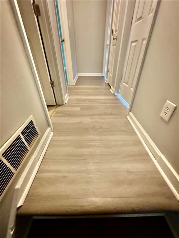 hall featuring baseboards and light wood-type flooring