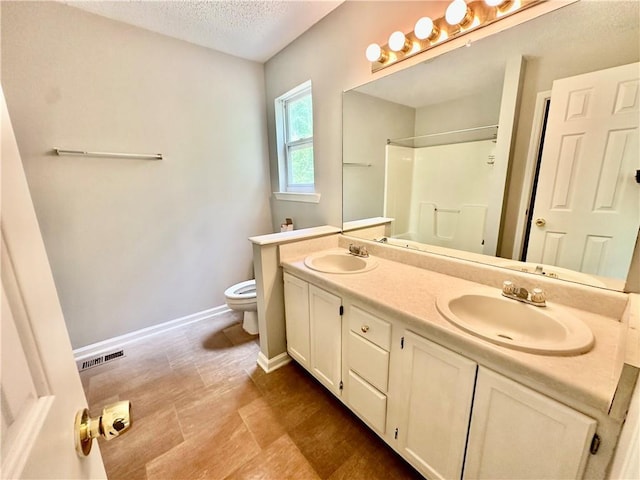 full bathroom with toilet, a textured ceiling, a sink, and a shower