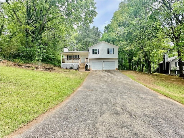 tri-level home featuring a porch, a front lawn, driveway, a chimney, and an attached garage