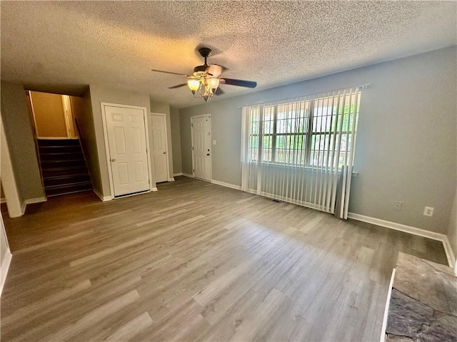 unfurnished bedroom with a textured ceiling, wood finished floors, and baseboards