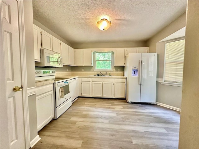kitchen featuring a textured ceiling, white cabinetry, light wood-style flooring, a sink, and white appliances