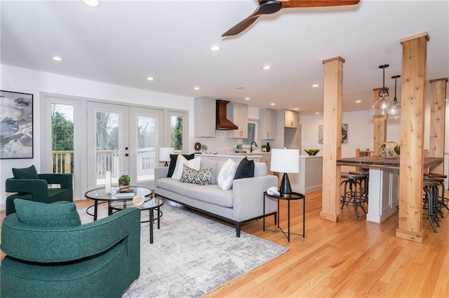 living room featuring ceiling fan, french doors, light hardwood / wood-style floors, and sink