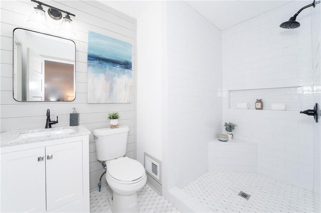 bathroom featuring a tile shower, vanity, and toilet