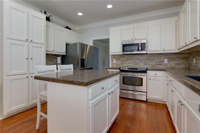 2995 Aspen Ridge Ct, Snellville, GA 30078 - kitchen featuring appliances with stainless steel finishes, a center island, white cabinets, ornamental molding, and tasteful backsplash