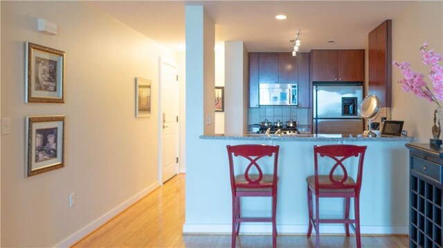 3338 Peachtree Rd NE Unit 1506, Atlanta, GA 30326 - kitchen with stainless steel appliances, tasteful backsplash, light wood-style floors, a breakfast bar, and baseboards