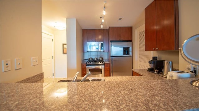 3338 Peachtree Rd NE Unit 1506, Atlanta, GA 30326 - kitchen featuring stainless steel appliances, a sink, decorative backsplash, brown cabinets, and stone countertops