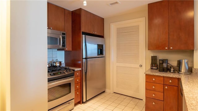 3338 Peachtree Rd NE Unit 1506, Atlanta, GA 30326 - kitchen featuring appliances with stainless steel finishes, light countertops, light tile patterned floors, and brown cabinets