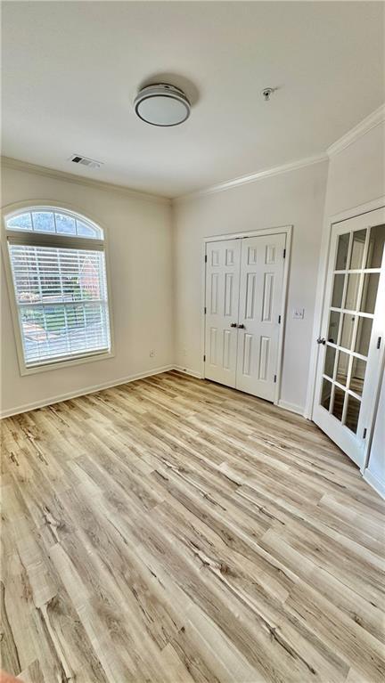 unfurnished room featuring baseboards, light wood finished floors, and crown molding