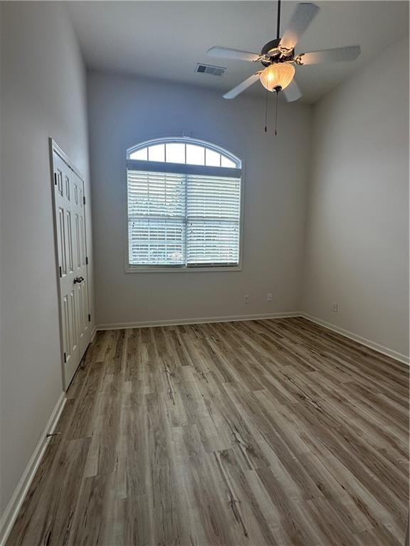 spare room featuring visible vents, baseboards, and wood finished floors