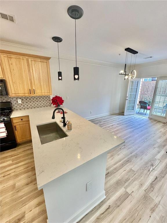 kitchen with light wood finished floors, a sink, crown molding, black appliances, and backsplash