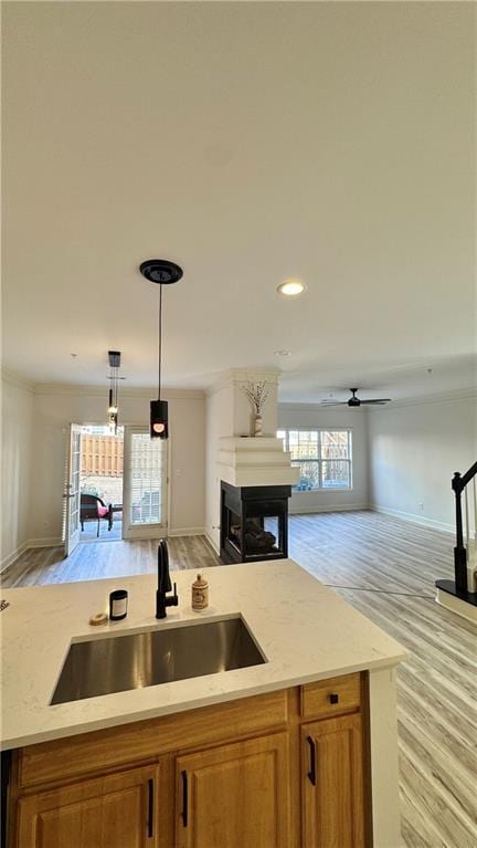 kitchen with brown cabinetry, open floor plan, a sink, and a multi sided fireplace