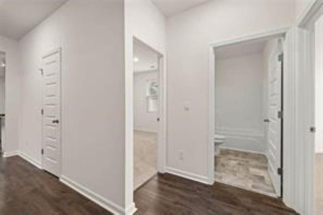corridor with baseboards and dark wood-type flooring
