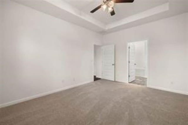 unfurnished room with baseboards, carpet flooring, a ceiling fan, and a tray ceiling