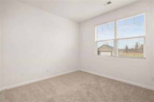 spare room featuring carpet floors and baseboards