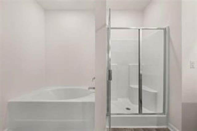 full bathroom featuring a garden tub and a shower stall