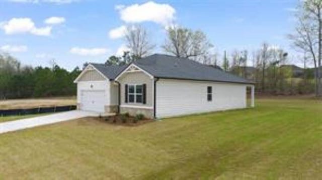 view of side of property featuring an attached garage, a yard, and driveway